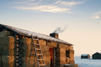 All autumn, neighbors watched her stack hay bales around her cabin — floor to roof, every wall. They called it foolish. They called it a waste. They said she’d freeze. Come January, the most skeptical man in the county rode four miles through six-below wind just to stand inside her house.