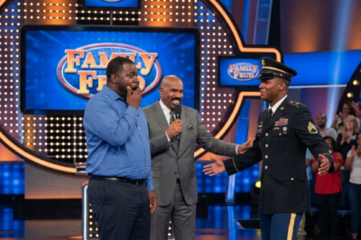 Steve Harvey stopped mid-sentence. Then he said: “He’s standing right there”. 19 years of silence. One stage. One uniform. One hug that broke 400 people.